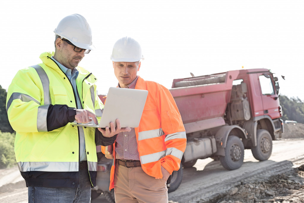 Architect and engineer checking project plans on a laptop at a construction site.