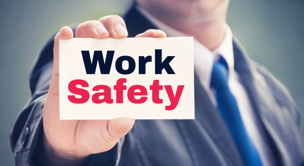 businessman holding small card with the words work safety in black and red